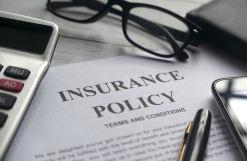 Glasses, Calculator, and Insurance Policy Documents on a Desk