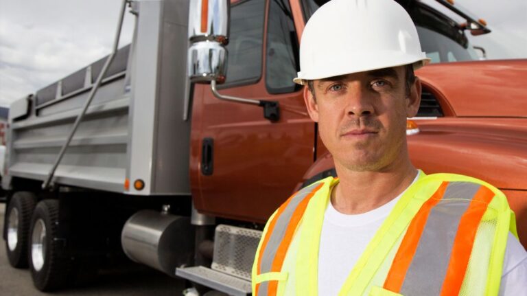 Truck Driver Next to a Semi Truck with Safety Vest and Hardhat