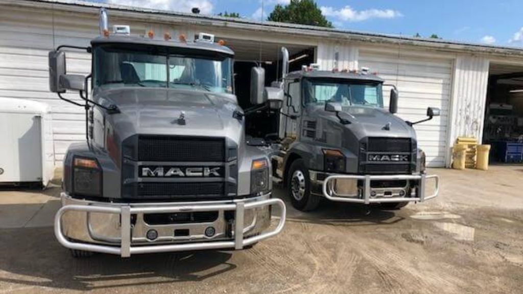 Two Gray Mack Trucks with RIGGUARD Grille Guards in Parking Lot