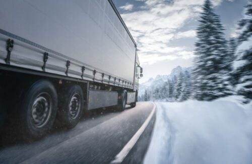 Close Up of the Side of a White Semi Truck Driving on a Snowy Road