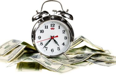 Silver Alarm Clock on a Pile of Cash