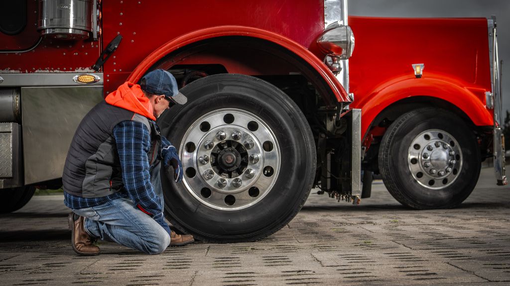 Mechanic Looking at Wheel of Red Semi Truck